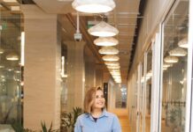 직장 내 스트레스 관리: 생산성 향상의 열쇠 woman in blue dress shirt and blue denim jeans standing beside brown wooden chair