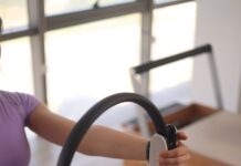 필라테스, 몸과 마음을 건강하게 가꾸는 현대인의 필수 운동 a woman sitting on the floor holding a steering wheel