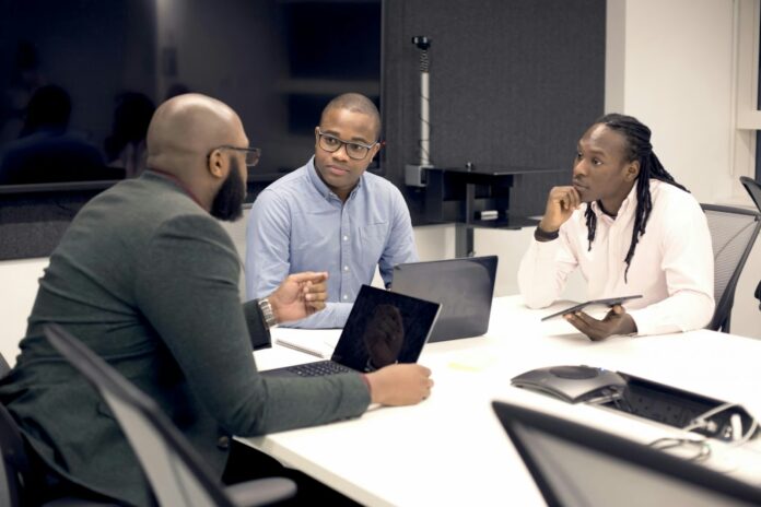 Photo by UK Black Tech a group of people sitting around a table with laptops