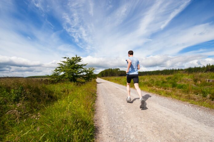 Photo by Jenny Hill man running on road near grass field