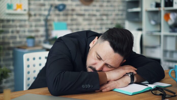 Photo by Vitaly Gariev a man leaning his head on his desk