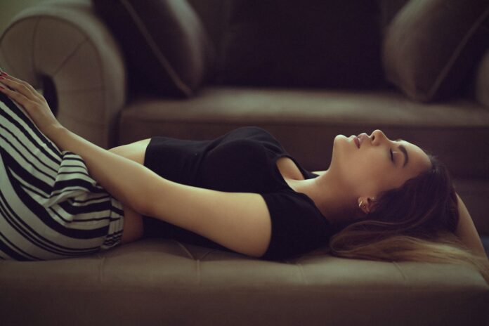 Photo by kayvan jabbarian woman in black and white stripe shirt lying on brown couch