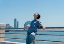 “깊은 잠이 주는 힘, 내 일상에 스며드는 건강 수면 루틴” Woman enjoys the sun with water and city views.