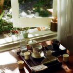 “마음도 건강하게” 일상 속 정신건강 지키는 새로운 트렌드와 실천법 Tea set arranged on a wooden tray by the window.