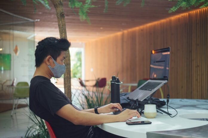 Photo by Paul Hanaoka man in black t-shirt sitting in front of laptop computer